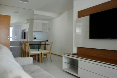 uma sala de estar com televisão e uma mesa com cadeiras em Flats Rosarinho Prince Prime no Recife