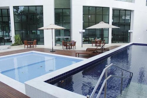 uma piscina num edifício com mesas e guarda-sóis em Flats Rosarinho Prince Prime no Recife