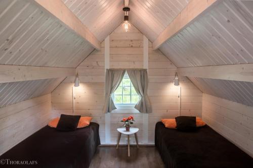 a attic room with two beds and a window at Glamping & Camping in Vestmannaeyjar