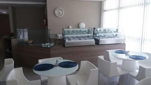 勒西菲的住宿－Flats Beach Class Boa Viagem Exclusive，一间设有白色椅子和桌子以及时钟的房间