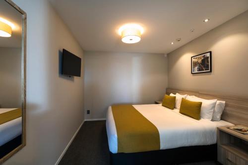 a hotel room with a bed and a mirror at Quest Petone in Lower Hutt