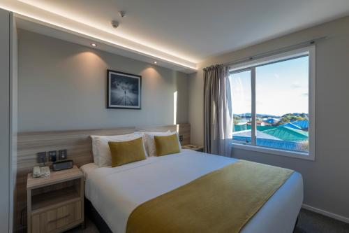 a bedroom with a large bed and a large window at Quest Petone in Lower Hutt