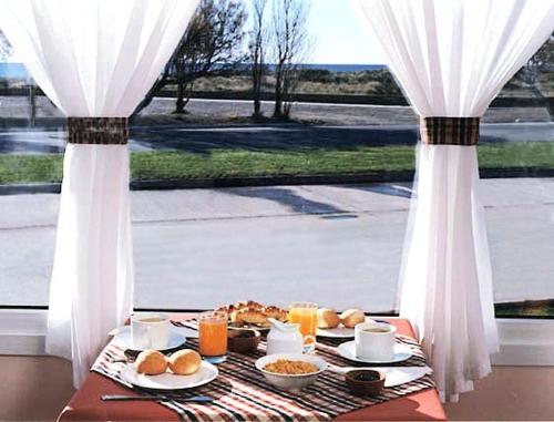 een tafel met eten en drinken op een tafel met een raam bij Hosteria Solar de la Costa in Puerto Madryn