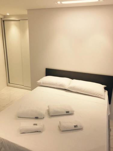 a white bed with two towels on top of it at Flats Jaqueira Prime in Recife