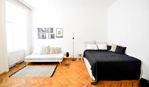 a bedroom with a bed and a white couch at Design apartment Degengasse in Vienna