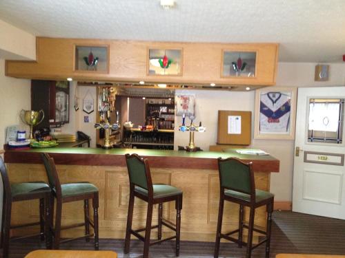 a kitchen with a bar with four chairs at Hall Park Hotel in Workington