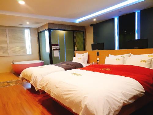 a bedroom with two beds and a tub in it at No.1 New Yorker Hotel in Jinju