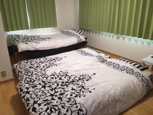 two beds in a room with white and black sheets at Kurashiki Base Inarimachi in Kurashiki