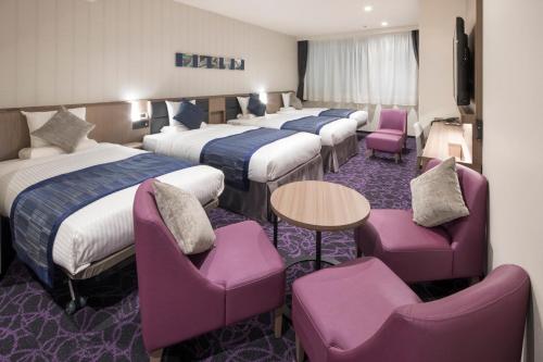 um quarto de hotel com quatro camas e cadeiras roxas em Hotel Mystays Gotanda Station em Tóquio