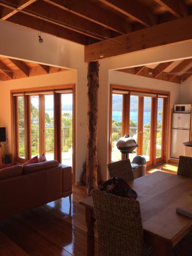 a living room with a table and chairs and windows at The Tree House in Alonnah