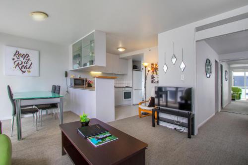 een woonkamer met een tafel en een woonkamer met een keuken bij Crown on Cintra Lane in Auckland