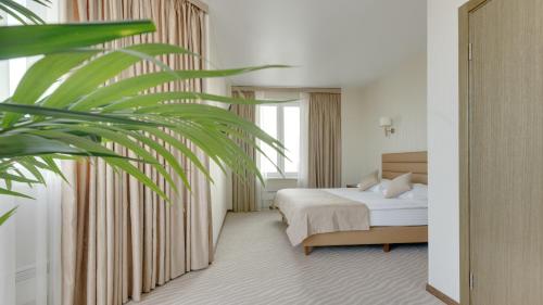 una habitación de hotel con una cama y una palmera en Gala Hotel, en Surgut
