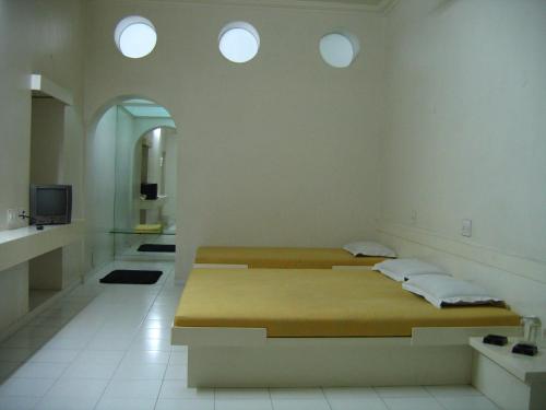 two beds in a room with three windows at Hotel Plaza (BOOKING FOR FOREIGN TOURIST ONLY) in Jālgaon