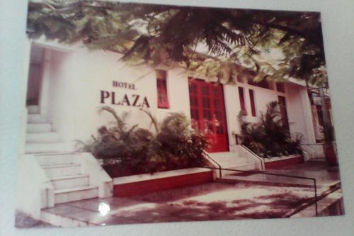 a white building with a red door and some plants at Hotel Plaza (BOOKING FOR FOREIGN TOURIST ONLY) in Jālgaon