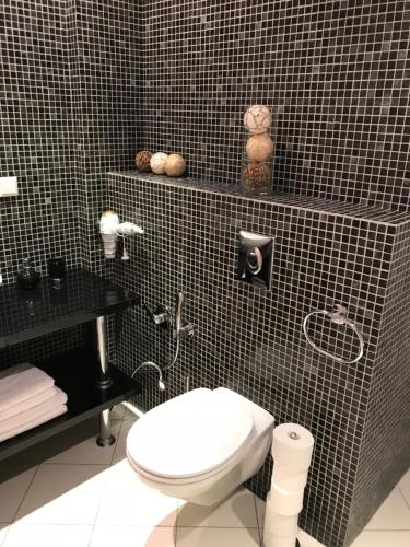 a bathroom with a toilet and a black tiled wall at Lux Apartment in Druskininkai