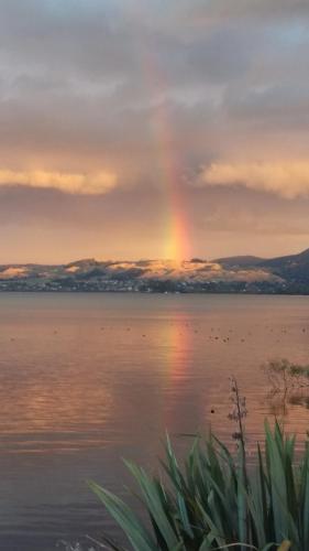 a rainbow in the sky over a body of water at Koutu Beach Bed and Breakfast in Rotorua