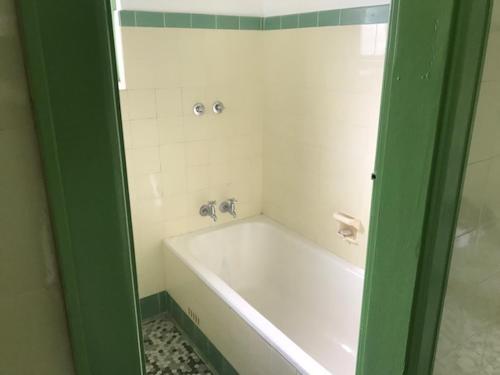 a white bath tub in a bathroom with a green door at Lakes and Ocean Hotel Forster in Forster