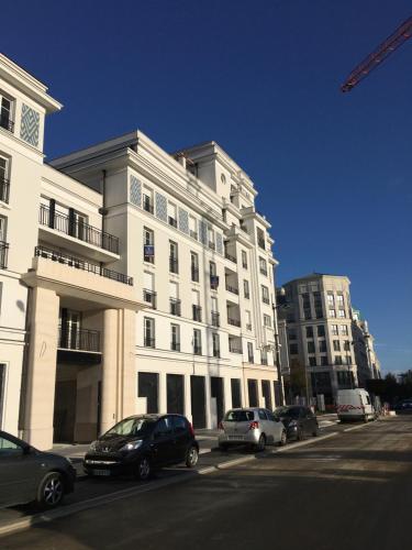 a large white building with cars parked in front of it at Sleep in Paris Val d'Europe in Chessy