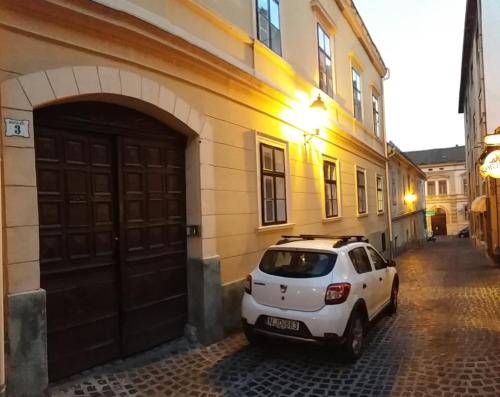 a white car parked in front of a building at Marilyn City Center in Pécs