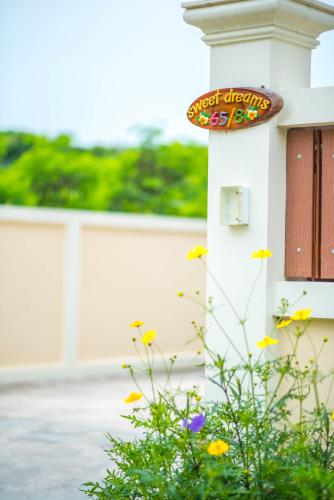 a sign on the side of a house with flowers at Sweet Dreams in Phetchaburi