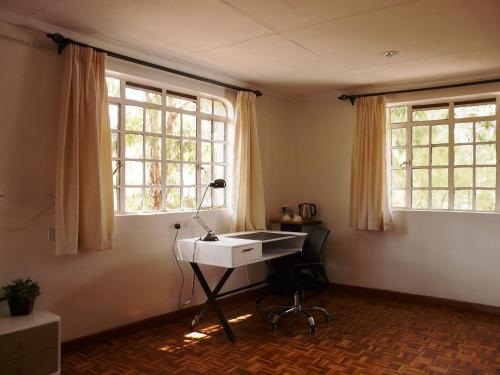 a desk in a room with two windows at Maison Mitwaba in Nairobi