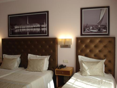 a hotel room with two beds and two pictures on the wall at Welcome In in Aveiro