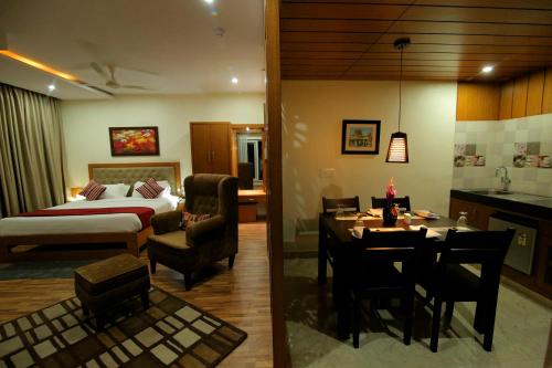 a hotel room with a bedroom and a dining room at Hotel Hampi International in Hospet