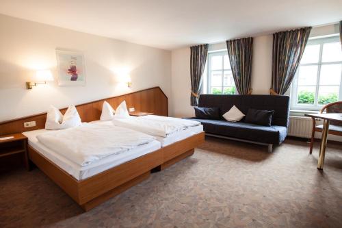 a bedroom with a large bed and a couch at Hotel Reussischer Hof in Schmölln