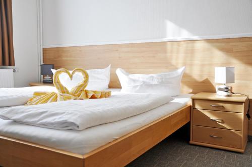 a bedroom with a bed with a heart pillow on it at Hotel Atlantik in Borkum