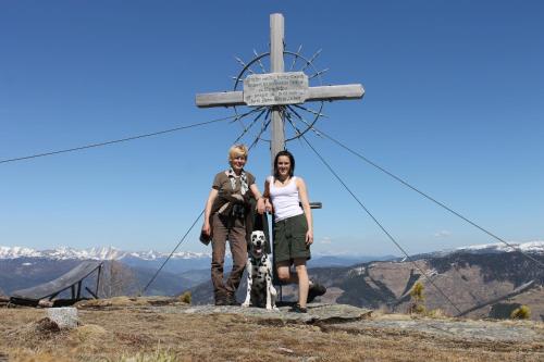 a man and a woman and a dog standing in front of a cross at Almhütte Kristabauer in Predlitz