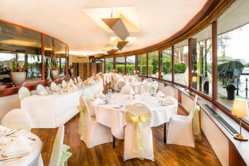 a restaurant with white tables and chairs and windows at Copthorne Hotel Manchester Salford Quays in Manchester