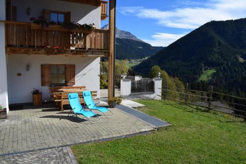 a patio with two chairs and a table and a balcony at Kellnerhof in Nova Levante