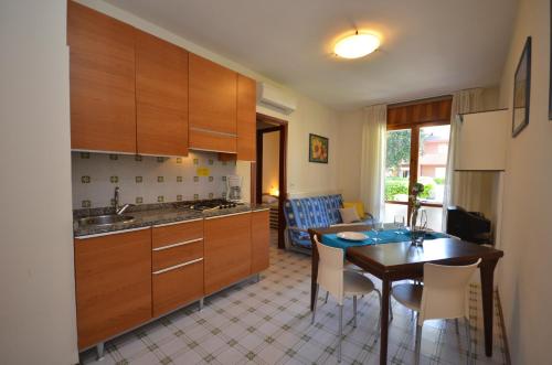 kuchnia z drewnianymi szafkami i stołem z krzesłami w obiekcie Villaggio Orchidee w Bibione