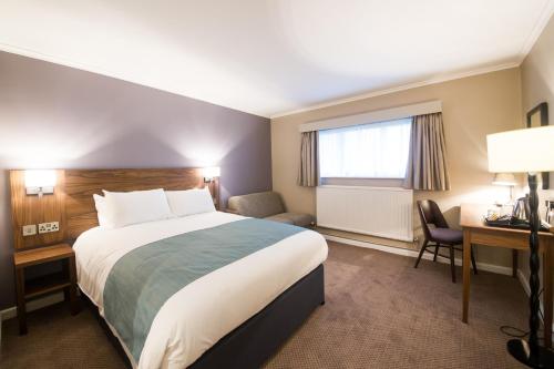 a hotel room with a large bed and a desk at The Beach Arms by Innkeeper's Collection in Oakley