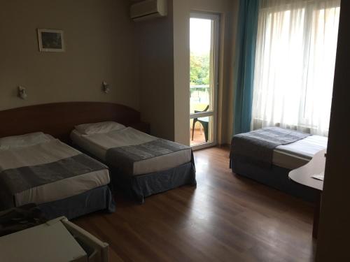 a hotel room with two beds and a window at Family Hotel Lazuren Briag in Burgas City