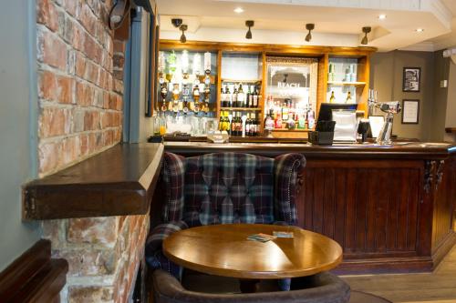 a bar with a wooden counter and a wooden table at The Beach Arms by Innkeeper's Collection in Oakley