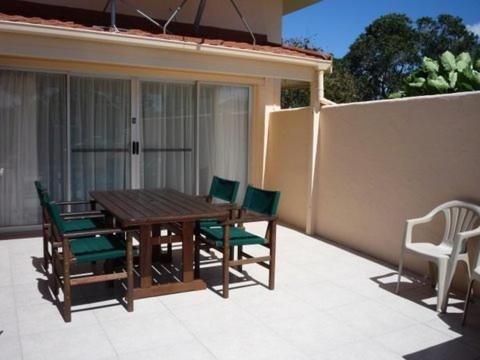 a wooden table and chairs on a patio at Paku Lodge Resort in Tairua