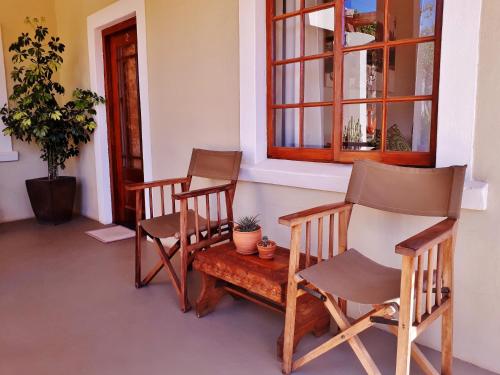 a porch with two chairs and a table and a window at Koedoeskloof Guesthouse in Ladismith