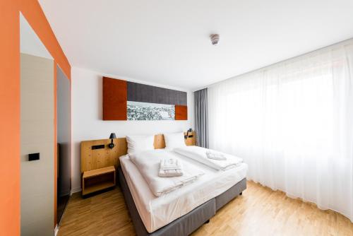 a bedroom with a bed and a large window at mk | hotel rüsselsheim in Rüsselsheim