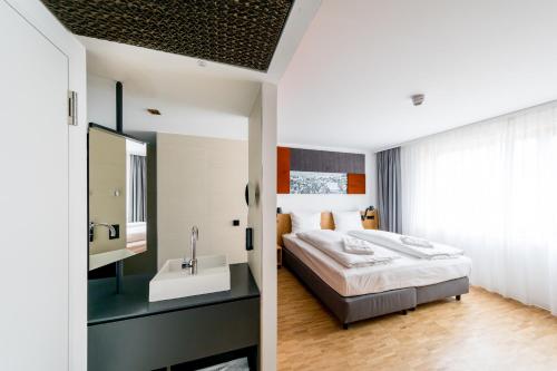 a bedroom with a large bed and a sink at mk | hotel rüsselsheim in Rüsselsheim