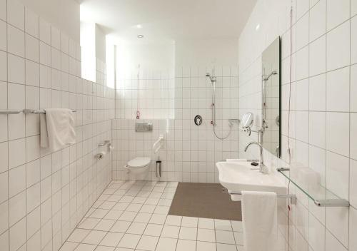 a white bathroom with a sink and a toilet at Katholische Akademie Schwerte in Schwerte