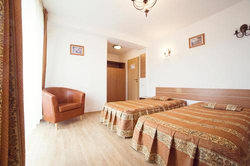 a hotel room with two beds and a chair at Pensiunea Comarnic-Moisa in Comarnic
