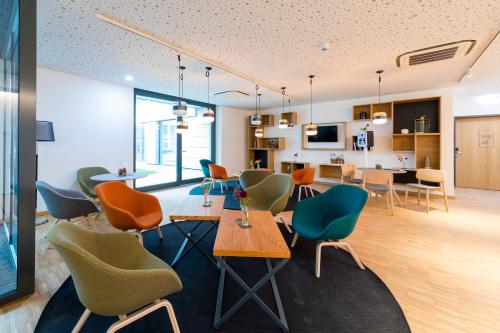 une chambre avec des chaises et des tables ainsi qu'une cuisine dans l'établissement mk | hotel rüsselsheim, à Rüsselsheim