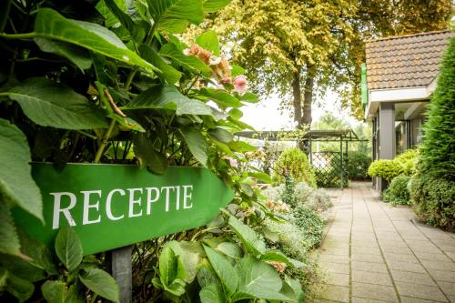 
a green and white street sign next to a garden at Campanile Hotel & Restaurant Rotterdam Oost in Rotterdam
