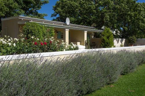 a house with a white fence and flowers at Auberge Clermont in Franschhoek