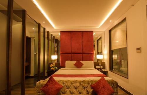 a hotel room with a bed with red pillows at Roopa Elite in Mysore