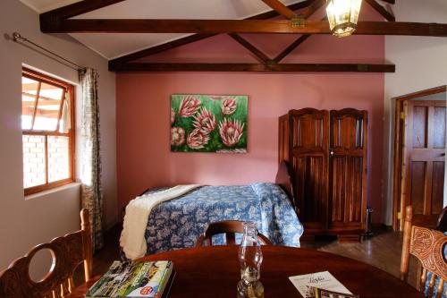 a bedroom with a bed and a table and a painting at Lentelus Guesthouse in George