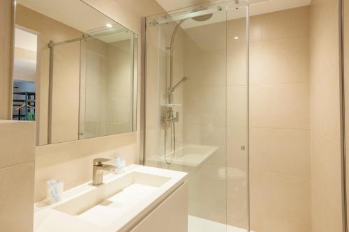 a bathroom with a shower, sink, and mirror at Hotel Restaurant des Maures in Collobrières