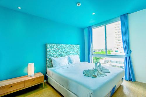 a blue bedroom with a bed and a window at Atlantis Residence in Jomtien Beach