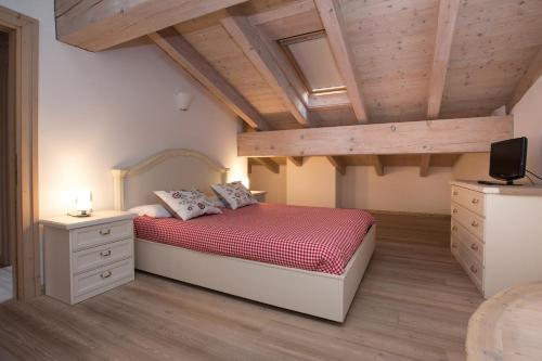 una camera da letto con letto con lenzuola rosse e soffitti in legno di Casa del Sol Apartaments a Bormio